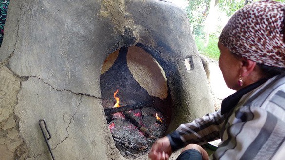 Рукия Маннонова печет традиционные национальные лепешки нон в тандыре. [Надин Бахром]