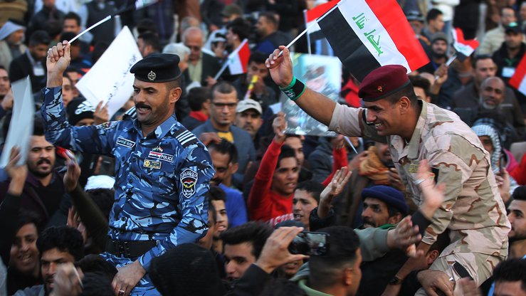 Iroqlik askar va politsiyachi Bag‘dodning Tahrir maydonida o‘z milliy bayrog‘ini ko‘tarib, ISHID bilan uch yil davom etgan urushdan so‘ng erishilgan g‘alabani nishonlamoqda, 10-dekabr. (Ahmad Al-Rubaye/AFP)