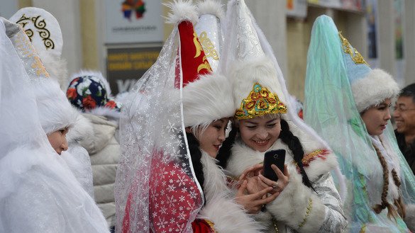 Қорқиз кийимидаги ёш аёллар Бишкек шаҳрида 2015 йил 31 декабр куни Янги йил арафасида ўтказилган парад вақтида мобил телефонларига тикилиб турибдилар. Хавфсизлик хизмати расмийларига кўра, экстремизм даъватчилари сўнгги йилларда Telegram ва Whatsapp каби смартфон иловаларидан фаол фойдаланишни бошлаганлар. (Вячеслав Оселедко/AFP)