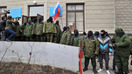 Yuzlariga niqob tutib olgan noma’lum shaxslar Qrimning Simferopol shahridagi Kasaba uyushmasi binosi oldida Rossiya bayrog‘ini ushlab turishibdi, 2014-yil, 1-mart. (Genya Savilov/AFP)
