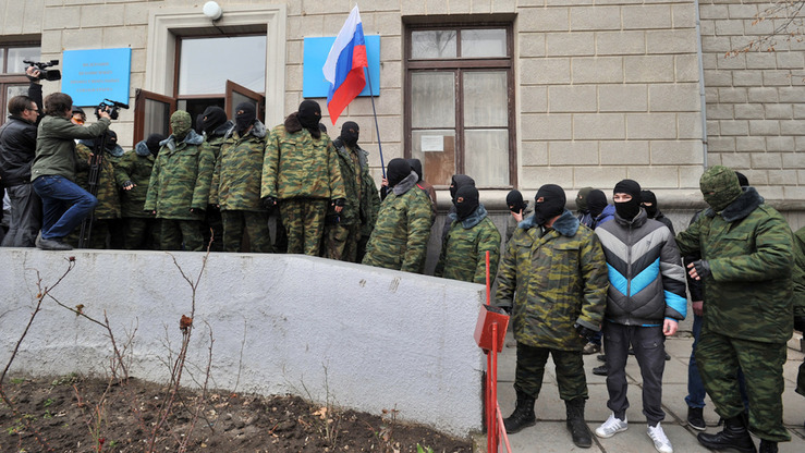 Юзларига ниқоб тутиб олган номаълум шахслар Қримнинг Симферополь шаҳридаги Касаба уюшмаси биноси олдида Россия байроғини ушлаб туришибди, 2014 йил, 1 март. (Геня Савилов/AFP)