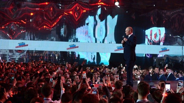 Тасвирда 15 март куни сайлов тадбирларида қатнашаётган Россия президенти Владимир Путин одамлар билан ҳазил-ҳузул қилиб тургани акс эттирилган. Путин гўё унинг ҳукумати қўллаб-қувватлаган Сурия режими бегуноҳ инсонларга зарар етказаётганидан бехабардек. Ўтган бир неча ҳафта ичида, Шарқий Ғутада 1300 дан ортиқ фуқаро қурбон бўлди, уларнинг кўпчилиги заҳарли газ ҳужумлари сабаб ҳаётдан кўз юмган. (Кремль)