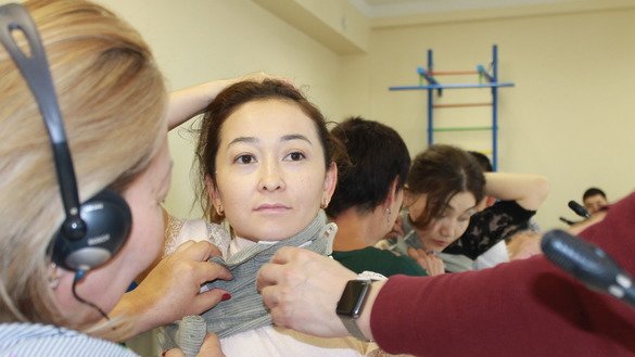Medics practice bandaging an underarm wound (with a bandage extending to the patient's neck). [Aydar Ashimov]