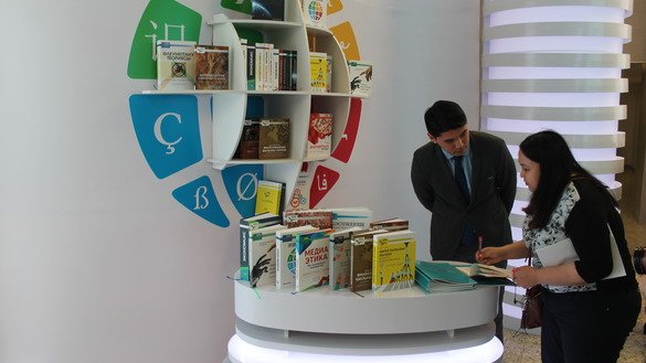 “Qozoq tilidagi 100 ta yangi darslik” loyihasi koordinatori Alixan Tuyebai 14-aprel kuni Ostonadagi ko‘rgazma tashrifchisiga tarjima qilingan kitoblarni ko‘rsatmoqda. (Aydar Ashimov)