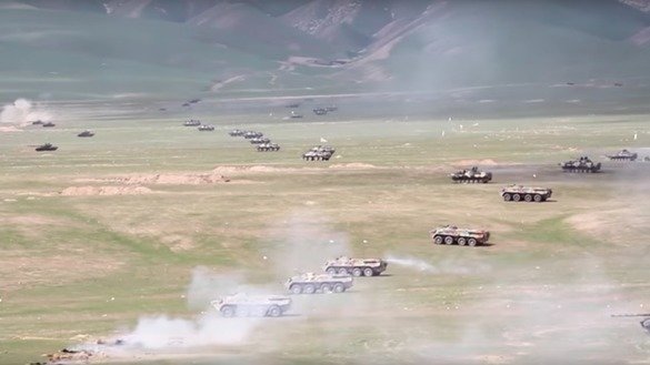 
Various Russian tanks and armoured personnel carriers are seen advancing across Tajik territory during a live fire exercise near Harbmaydon in 2017. [Russian Ministry of Defence]        