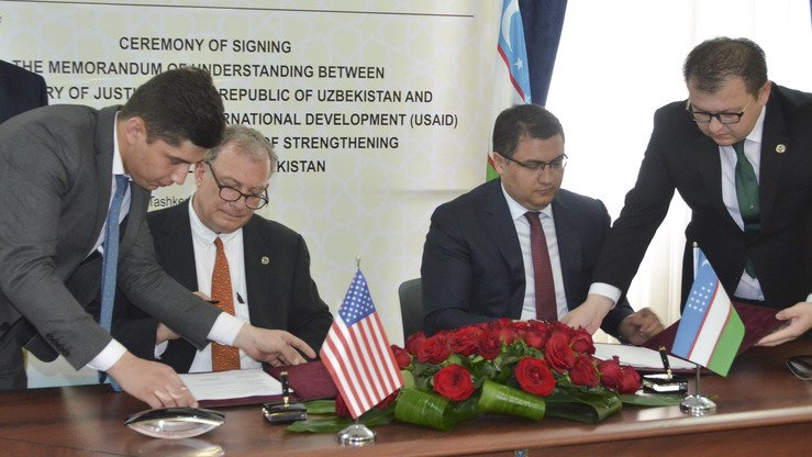 USAIDнинг Осиё бўйича раҳбари ёрдамчисининг ўринбосари Хавиер Пиедра ва Ўзбекистон адлия вазири Руслан Давлетов 8 июнь куни Тошкентда мамлакатда суд-ҳуқуқ тизимини қўллаб-қувватлаш бўйича ўзаро англашув меморандумини имзоладилар. (АҚШнинг Ўзбекистондаги элчихонаси)
