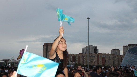 Девочка размахивает казахским флагом над толпой гуляющих. [Айдар Ашимов]