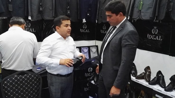 O‘zbekistonning “Ideal” poyabzal ishlab chiqarish korxonasining rahbari Akram Karimov (chapda) So‘g‘d-2018 xalqaro yarmarkasida mehmonlar bilan suhbatlashmoqda, Xo‘jand, 6-iyul. (Negmatullo Mirsaidov)
