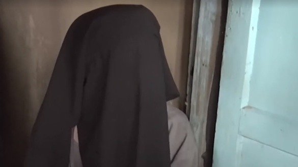 “Current Time” telekanalining Qirg‘izistondagi “Yaqin inkor” guruhi a’zolari haqidagi 23-iyul kungi videolavhasidan olingan kadr. Guruh a’zosi Baxtigul Abdraxmanova yuzini yopgan holatda uyiga kelgan davlat organlari xodimlari bilan suhbatlashmoqda. Baxtigul va uning turmush o‘rtog‘i Jergal farzandlarini maktabga berishdan bosh tortganlari uchun uch yillik qamoq jazosiga hukm qilingan edilar. (File)