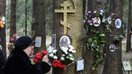Сталин давридаги қатағон қурбонларининг суратлари илинган дарахтга гул боғлаётган аёл, 30 октябрь. Мазкур мемориал мажмуа Санкт-Петербург яқинидаги ўрмонли ҳудудда жойлашган. (Олга Малцева/AFP)