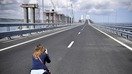15 май куни аёл 19 километрлик Керч бўғозидан ўтувчи Қрим кўпригининг очилиш маросими олдидан суратга олмоқда. Кўприк жанубий Россияни Москва аннекция қилган Қрим яримороли билан боғлайди. (Александер Неменов/AFP)