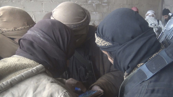 ID tomonidan 13-dekabr kuni Telegram tarmog‘ida e’lon qilingan suratda Suriyada smartfonga tikilib turgan bir guruh jangarilar tasvirlangan. (File)
