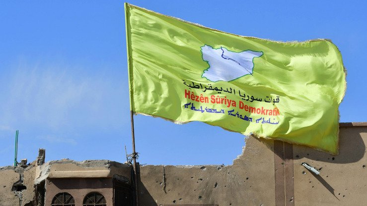 AQSH qoʻllovidagi Suriya demokratik kuchlari (SDK) 23-mart kuni Suriyaning Bogʻuzidagi bino tomiga oʻz bayrogʻini oʻrnatmoqda. Qishloqda ISHIDning qoldiqlari butkul yoʻq qilindi. ID jangarilari soʻnggi tayanch nuqtasidan siqib chiqarilar ekan, kurdlar boshqaruvidagi kuchlar besh yillik kurashdan soʻng, nihoyat ID “xalifaligi” tugatilganini eʼlon qildilar. (Juzeppe Kakache/AFP)