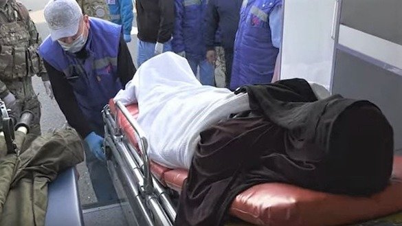 An ill woman wearing a niqab is lifted out of of a vehicle before her return to Kazakhstan. Her repatriation was part of Operation Jusan-2 (Bitter Wormwood 2), which took place May 7 and 9. The screenshot is from a KNB video.