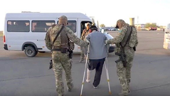 Казахстанца, примкнувшего к ИГ и потерявшего ступню в боях, ведут к автобусу. Спецоперация «Жусан-2» («Горькая полынь-2»), Сирия, 7 и 9 мая. Стоп-кадр из фильма КНБ.