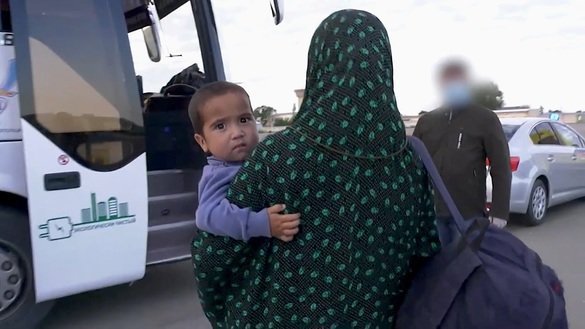 A woman with a child can be seen during an evacuation of Kazakhs from Syria in May. Kazakh authorities detained four evacuated women on suspicion of terrorism. The screenshot is from a KNB video.