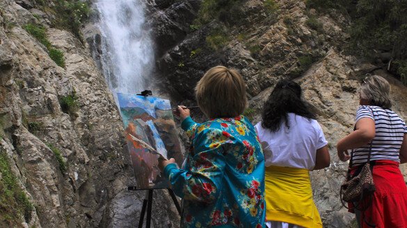 Женщина пишет картину у водопада «Чаша Манаса», туристы любуются природой. Ущелье Барскаун, Иссык-Кульская область, 3 июля. [Айдар Ашимов]
