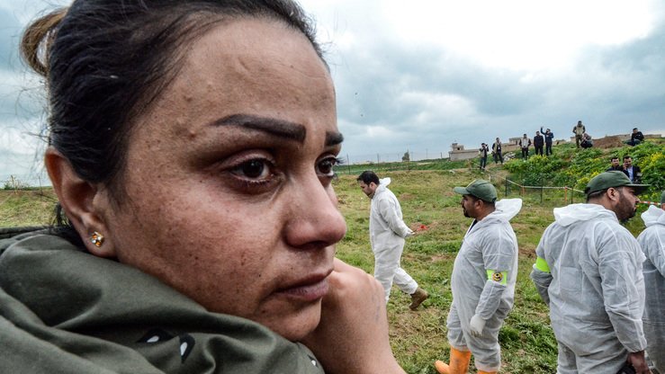 Sinjar tumani, Kuju qishlogʻida ID tomonidan oʻldirilgan yuzlab yazidiylarning ommaviy qabrlarini eksgumatsiya qilish vaqtida hududni koʻzdan kechirayotgan mutaxassislarni kuzatayotgan iroqlik yazidiy ayol, 15-mart. (Zayd al-Ubaydiy/AFP)