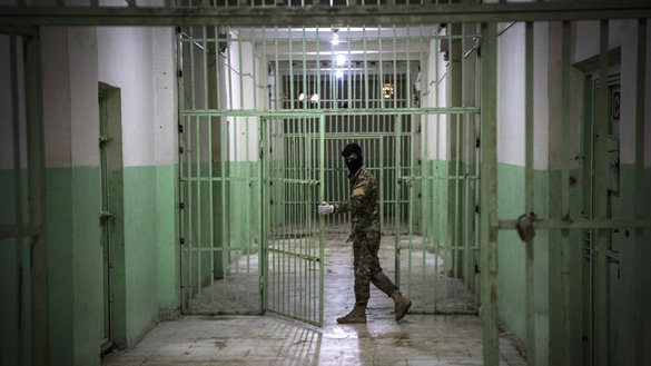 A member of the Syrian Democratic Forces stands guard in a prison where men suspected to be affiliated with IS are jailed in north-east Syria. [Fadel Senna/AFP]