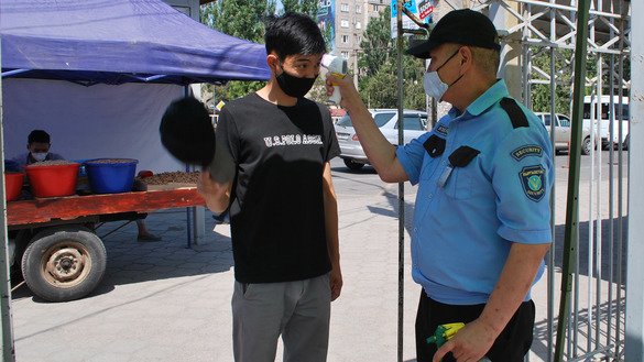 A security guard checks a visitor's temperature outside the Madina Market in Bishkek July 13. [Maksat Osmonaliyev]