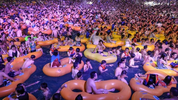 Посетители наблюдают за представлением, прохлаждаясь в бассейне. Ухань, Китай, 15 августа. [STR/AFP]