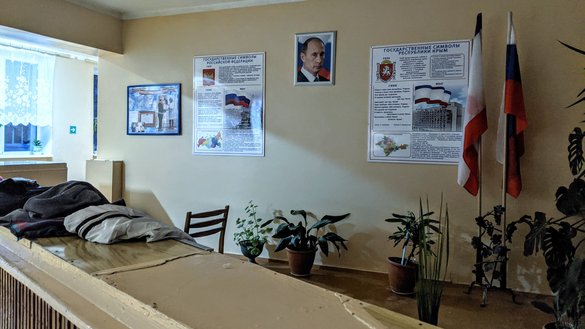 A portrait of Russian president Vladimir Putin hangs on a wall at I. I. Berezenyuk Secondary School in Koktebel, along with other Russian paraphernalia, on February 26. Schools have been required to display these items since Russia annexed the Crimea in 2014. [Yevgenij Gordienko/Caravanserai]