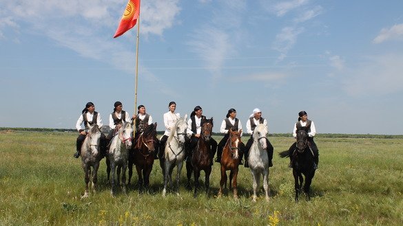 A Kyrgyz female horseback rider performs stunts alongside her male teammates. [Aydar Ashimov]