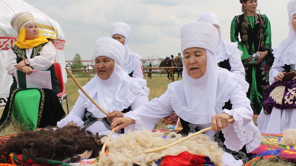 Women in Kazakh folk costumes process wool while singing. [Aydar Ashimov]