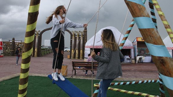 A tourist from Poland (left) and her Kazakh translator share a two-person Kazakh swing. Tourists from various countries attended the festival to learn more about Kazakhstan and its cultural heritage. [Aydar Ashimov]