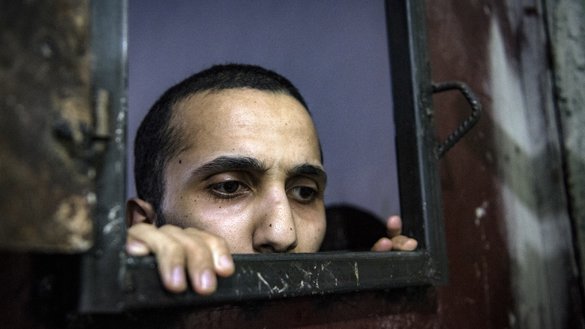 Заключенный, подозреваемый в принадлежности к ИГ, выглядывает в отверстие камеры. Эль-Хасака, 26 октября. [Фадель Сенна/АФП]