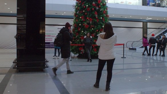 Молодые люди фотографируются на фоне новогодней елки в одном из супермаркетов. Шымкент, 19 декабря. [Айдар Ашимов]