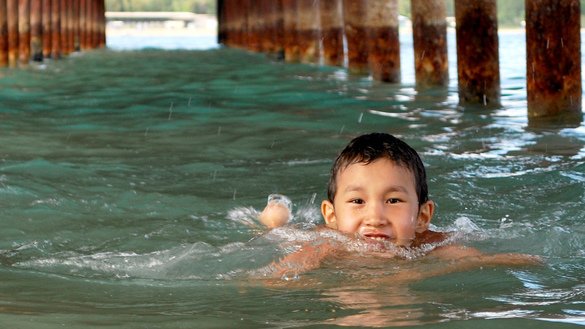 Aman, a nine-year-old from Bishkek, swims between the iron columns of a pier on Lake Issyk-Kul. For many children, the pandemic means canceled travel and vacations. Cholpon-Ata, Issyk-Kul Province, July 23. [Maksat Osmonaliyev]