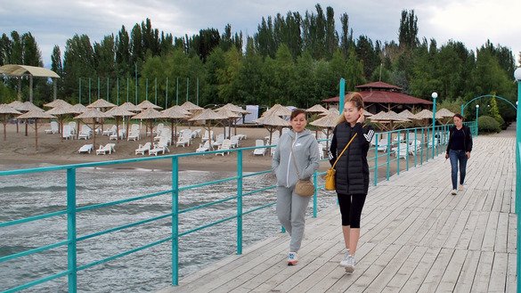 Vacationers stroll down the pier of the Marco Polo resort. This year no tourists from Russia or Kazakhstan are visiting, said Yevgeny, the hotel manager. "But we're operating on domestic tourism. Right now there are 70 guests. This time last year there were 520," he said. Boz-Beshim, Issyk-Kul Province, July 26. [Maksat Osmonaliyev]