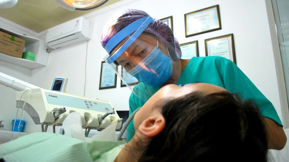 Aigul Tokoyeva, a dental therapist in Bishkek, uses a face shield to protect herself at work on August 19. Protective masks, face shields and gloves make up the standard equipment for health workers. [Maksat Osmonaliyev]