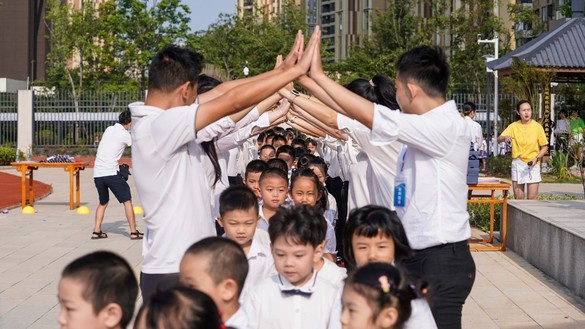 Учителя приветствуют учащихся начальной школы в первый день нового семестра. Ухань, Китай, 1 сентября. [STR/AFP]