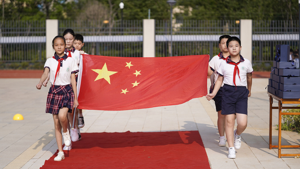 Ученики начальной школы держат национальный флаг во время церемонии поднятия флага. Ухань, Китай, 1 сентября. [STR/AFP]