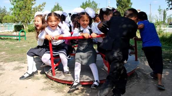 During recess, the first-graders play on a merry-go-round. September 1, K. Ibraimaliyev School, Kurpuldok village, Panfilov District, Chui Province. [Maksat Osmonaliyev]