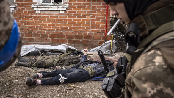 A Ukrainian soldier walks past the bodies of Russian soldiers after Ukrainian troops retook the village of Mala Rogan, east of Kharkiv, on March 30. [Fadel Senna/AFP]