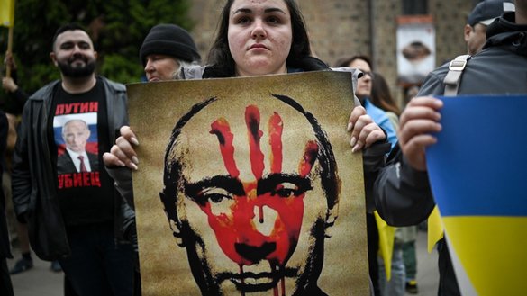 A woman on April 28 in Sofia, Bulgaria, holds an image depicting Russian President Vladimir Putin and the word 'killer' during a demonstration demanding Bulgaria provide arms and ammunition to Ukraine. [Nikolay Doychinov/AFP]